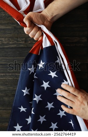 Hand Holding American Flag Close-Up: Patriotism and National Pride in Dark Wooden Background