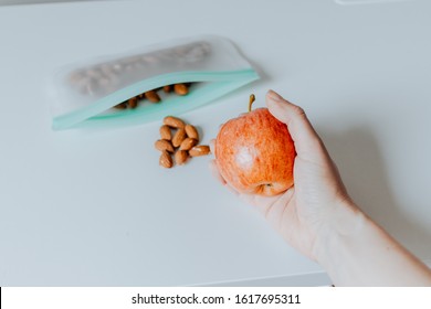 Hand Holding Apple With Almonds In Reusable Ziplock Bag