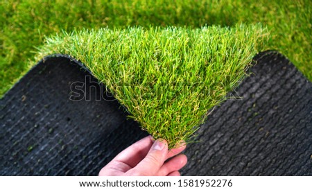 Hand holding an artificial grass roll. Greenering with an artificial turf.