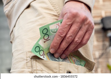 Hand Holding Australian Dollars 100 Banknotes In The Pocket Of Cargo Shorts. Tradie Finance Concept.