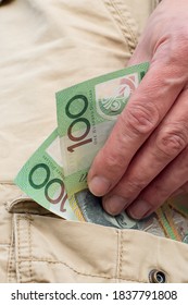 Hand Holding Australian Dollars 100 Banknotes In The Pocket Of Cargo Shorts. Tradie Finance Concept.