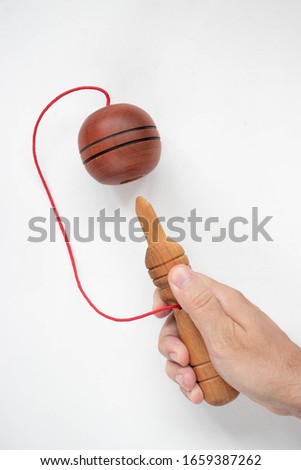 A hand holding a ball in a cup toy on a white background