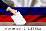 Hand holding ballot in the ballot box with Russia flag in the background. Presidential elections of the Russian Federation