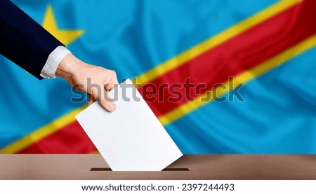 Hand holding ballot in voting ballot box with Democratic Republic of the Congo flag in background. Presidential elections of the democratic republic of the congo