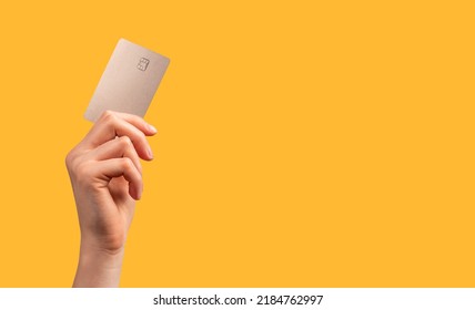 Hand holding bank card with chip over bright orange promo background with copy space for text. High quality photo - Shutterstock ID 2184762997