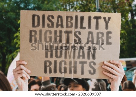 Man’s hand holding a banner with the text ‘Disability rights are human rights.’ Perfect for showcasing support or protest for the rights of people with disabilities worldwide