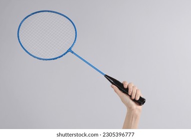 Hand holding batbinton racket on gray background