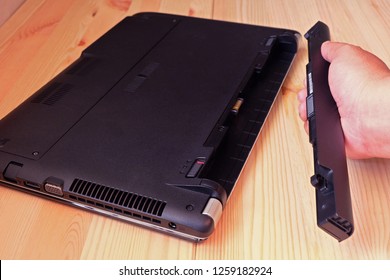 Hand holding battery Remove of laptop computer on wooden floor, Upgrade and Repair computer concept.