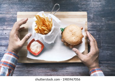 Hand Holding Beef Burger On Table, Top View 