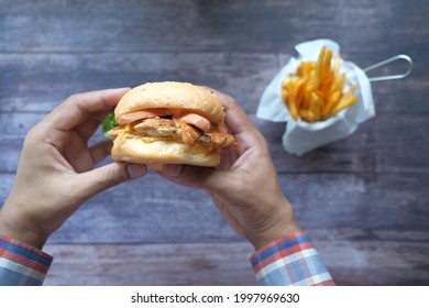 Hand Holding Beef Burger On Table Top Down 