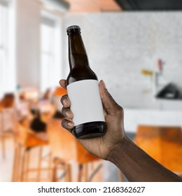 Hand Holding A Beer Bottle With Black Label On Restaurant Cafe Pub Background