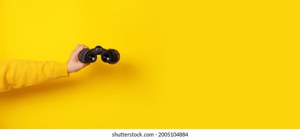hand holding binoculars over yellow background, panoramic mock-up - Shutterstock ID 2005104884