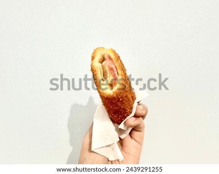 Hand holding bitten risol; mayo risol filled with sliced beef with egg with mayonnaise sauce