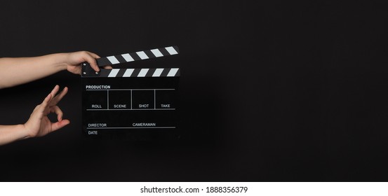 Hand is holding Black clapper board or movie slate on black background.Other hand do A ok or okay sign.