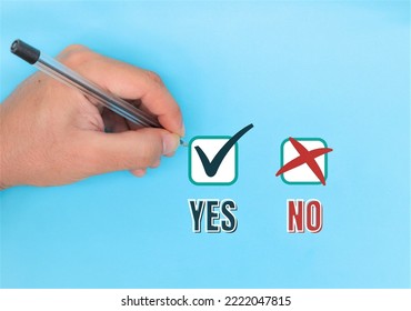 Hand Holding Black Pen Pointing Or Indicating Yes Or Correct V Sign On Blue Background. Concept Of Making Right Decisions, Right Or Wrong