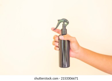 hand holding black plastic spray bottle. select focus.