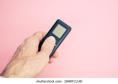 A Hand Holding A Black Remote Controller On Pastel Pink Background For A Copy Space