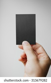 Hand Holding Black Vertical Business Card On The Grey Blurred Ba