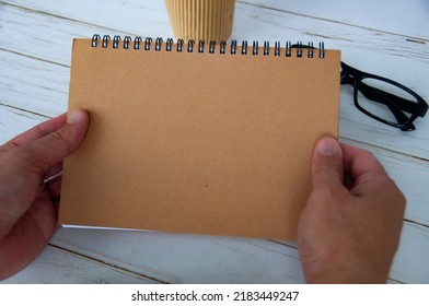 Hand holding blank brown notepad with space customizable for text or ideas. Copy space for ideas
