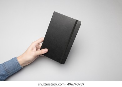 Hand holding blank cover of notebook with rubber band, Mock-up.