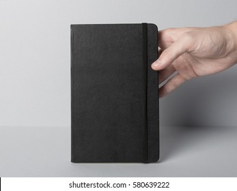 Hand holding blank cover of notebook with rubber band, Mock-up / Close-up