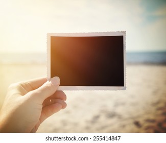 A Hand Is Holding Up A Blank Photo Snapshot At A Sunny Beach To Add Your Own Photo Or Message In The Area.