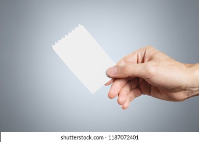 Hand Holding A Blank Ticket On Grey Background