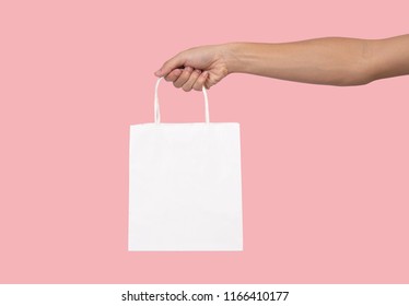 Hand Holding Blank White Paper Bag For Mockup Template Advertising And Branding Isolated On Pink Background. 