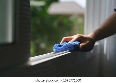 Hand holding blue microfiber cloth for cleaning dust on the glass window rail