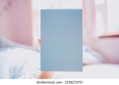 Hand Holding A Blue Paperback Book With Blank Cover With Space To Place Text.