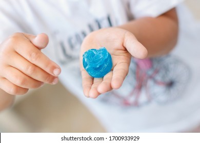 Hand Holding A Blue Slime On A White Background. Kid Game With Sticky Slime Pulling Toy