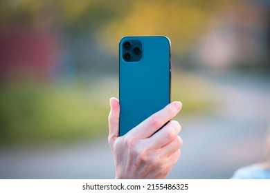 Hand Holding Blue Smartphone. Back Side Of The Phone