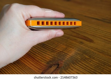 hand holding blues harmonica against wooden background