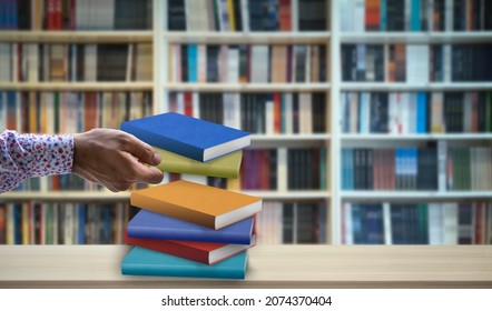 Hand Holding Book In Front Of Blurry Library Background