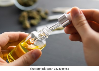 Hand holding bottle of Cannabis oil in pipette, natural herb, medical marijuana concept, CBD cannabis OIL. hemp product, close up,