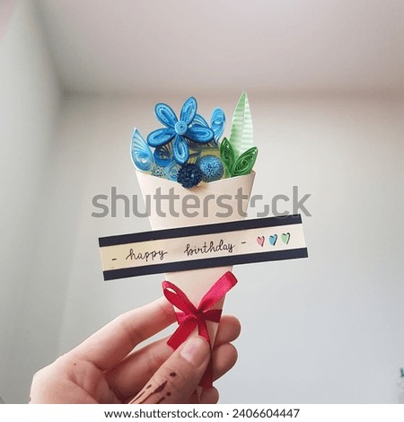 Hand holding a bouquet of blue paper quilling flowers with 