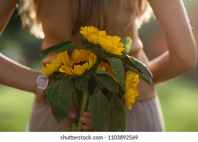 Woman’s Hand Holding Bouquet Of Sunflowers Behind Her Back