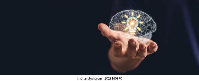 Hand holding brain with bright light bulb. Business success idea or solution concept. Thinking power of business person or professional. Working, studying or learning inspiration
