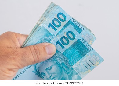 hand holding brazilian money with white background