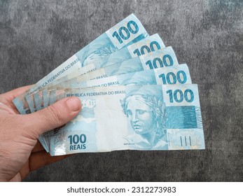 Hand holding Brazilian one hundred reais banknotes. Finance concept. - Shutterstock ID 2312273983