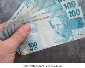 Hand holding Brazilian one hundred reais banknotes. Finance concept. - Shutterstock ID 2315193763