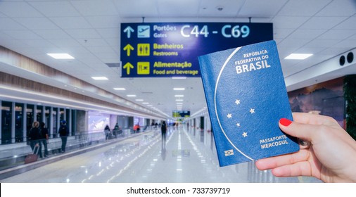 Hand holding a Brazilian passport and modern airport terminal and passengers in the background