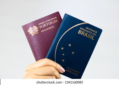 Hand holding Brazilian passport (Translation "Brazil Republic federal mercosul passport") and portuguese passport (Translation "European Union Portugal passport").
