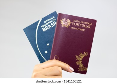 Hand holding Brazilian passport (Translation "Brazil Republic federal mercosul passport") and portuguese passport (Translation "European Union Portugal passport").