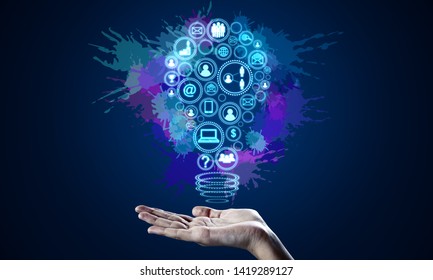 Hand holding bright digital social media light bulb on blue background. Communication and innovation concept
