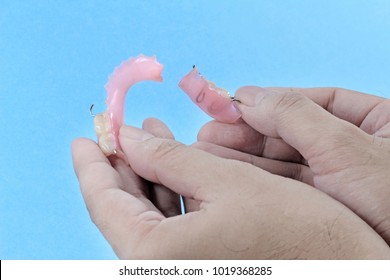 Hand Holding Broken Plastic Dentures.