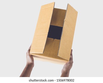 Hand holding brown box isolated on gray background.