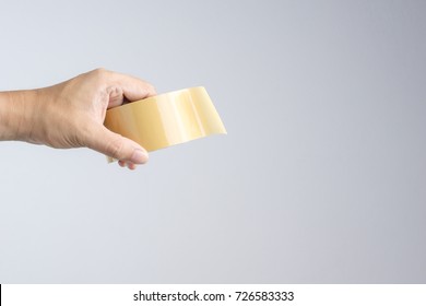 Hand Holding Brown Packaging Tape Roll On White Background