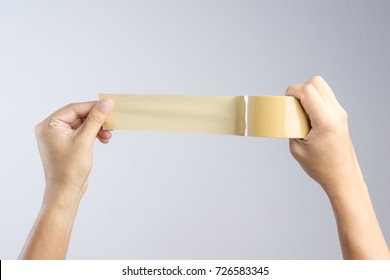 Hand Holding Brown Packaging Tape Roll On White Background