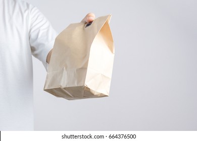 Hand Holding Brown Paper Bag On White Background